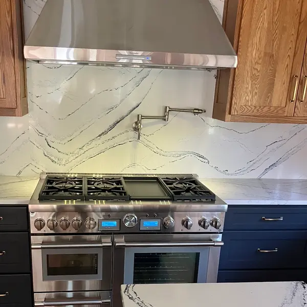 Finished kitchen remodel with a professional range, stainless hood and quartz backsplash