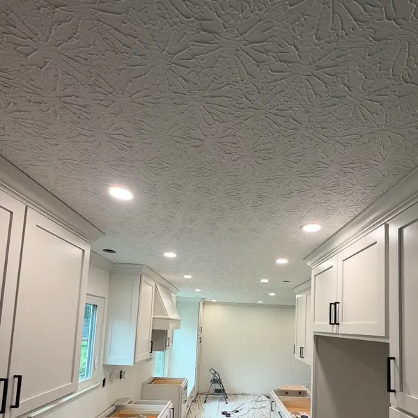 Kitchen renovation in progress with new recessed lights across the ceiling and white cabinets installed