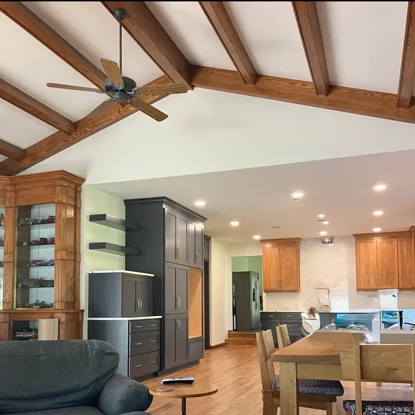 Open living room and kitchen with a ceiling fan on a vaulted beamed ceiling and recessed lights over the kitchen